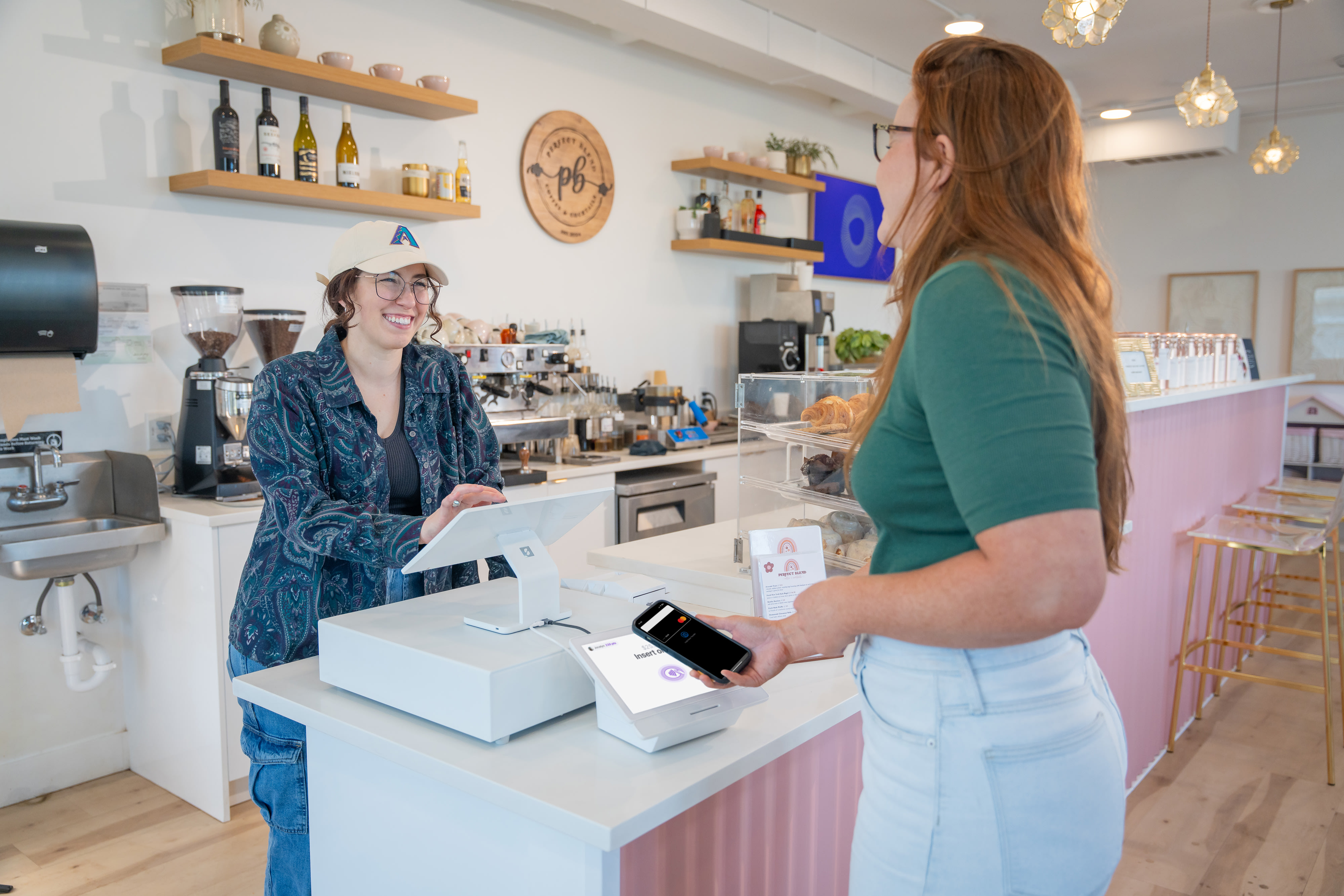 Customer paying with their phone at a restaurant POS with coffee shop worker.