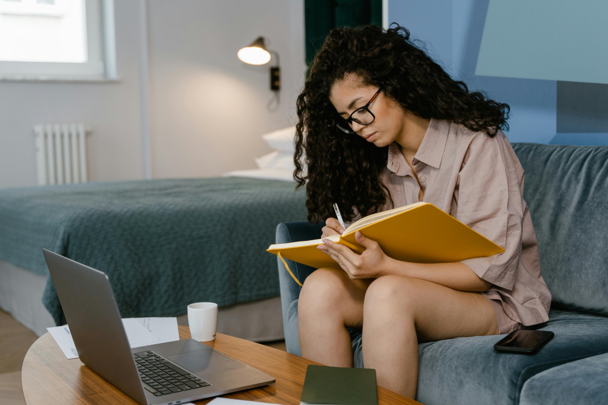 Frau arbeitet von zu Hause aus mit Laptop und Block