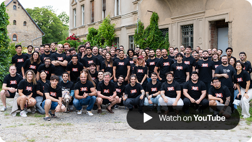 A large group of SumUp team members wearing black Hack Week 2025 t-shirts pose together outside a historic building, smiling at the camera, with a 'Watch on YouTube' button overlay in the corner.