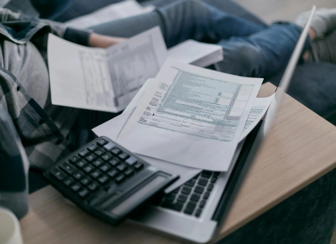 Steuerdokumenten, einem Taschenrechner und einem Laptop auf einem Tisch