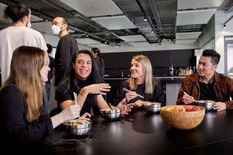 Photo of SumUp's Berlin office kitchen area with a group of diverse employees eating lunch
