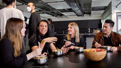 Photo of SumUp's Berlin office kitchen area with a group of diverse employees eating lunch