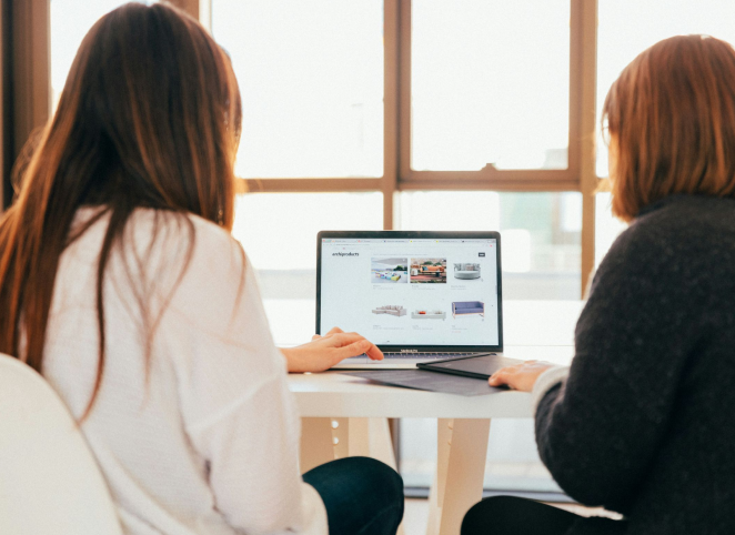 Zwei Frauen sitzen am Tisch vor einem Laptop