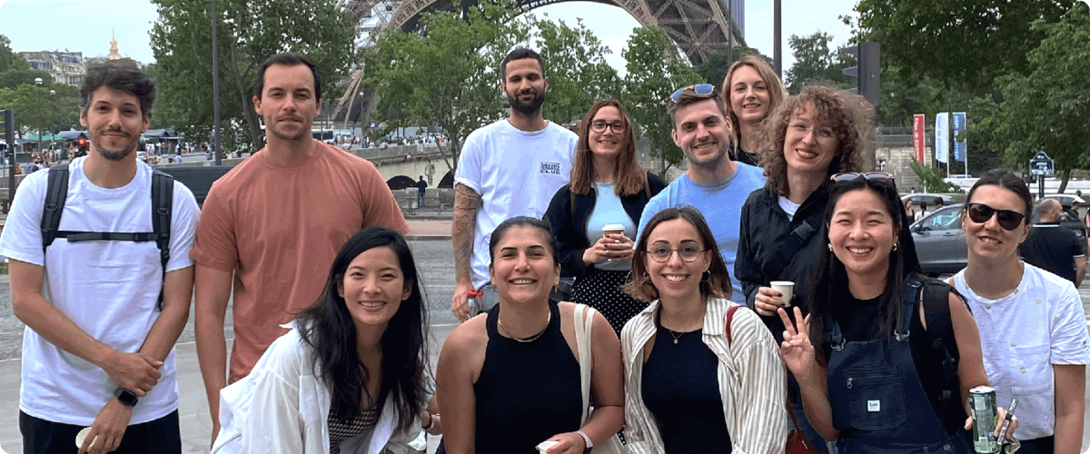A group of SumUppers smiling for a photo in front of the iconic Eiffel Tower in Paris.