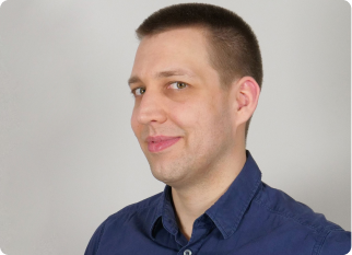 A male SumUpper with short brown hair, wearing a navy blue button-up shirt, looks slightly to the side with a subtle smile with a neutral grey background - image is related to a blog on neurodiversity and inclusion at SumUp.