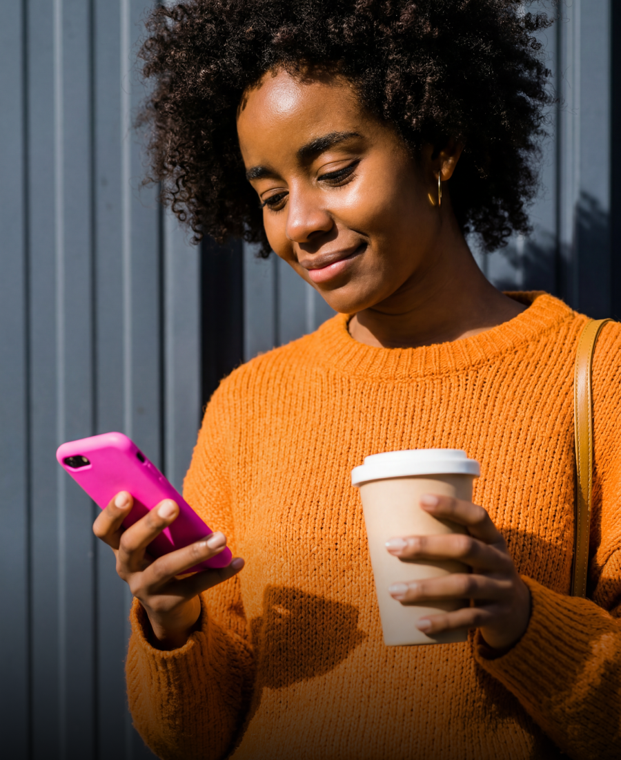 Iemand houdt een kop koffie vast en kijkt naar een telefoon