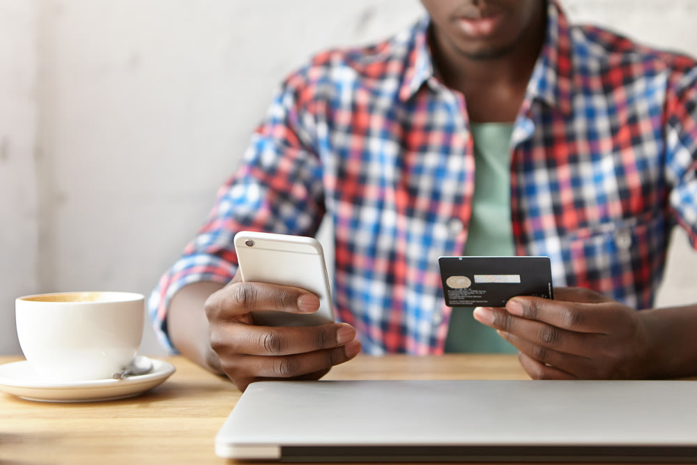 Mann bezahlt mit Kreditkarte über sein Smartphone online