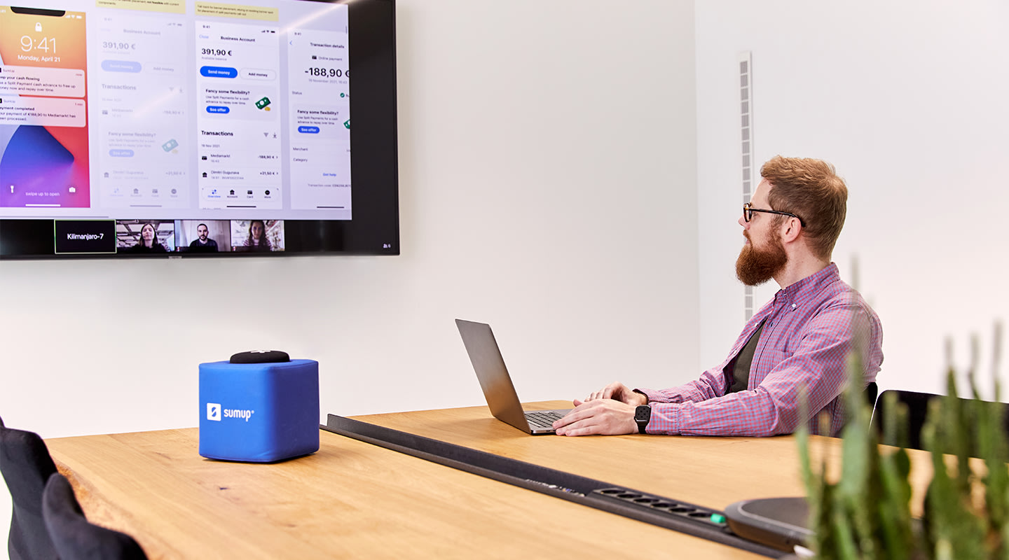 Male SumUpper working sitting in front of a laptop while talking to his team working remotely