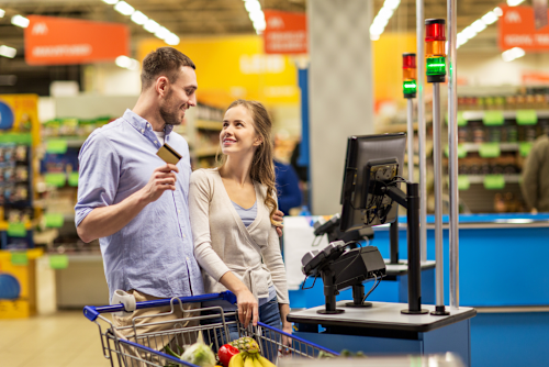 A man and woman happily use their card to buy groceries.