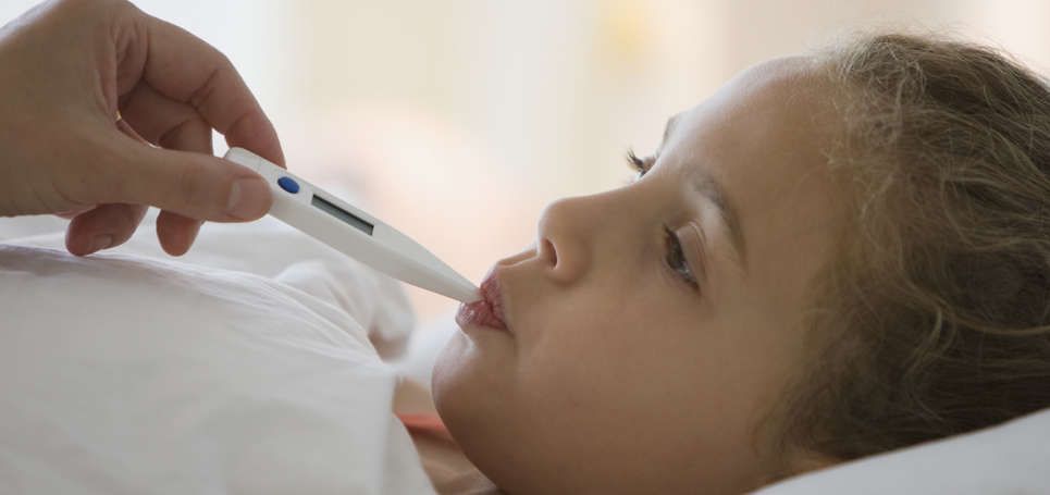 Petite fille allongée, en train de faire prendre sa température par la bouche 
