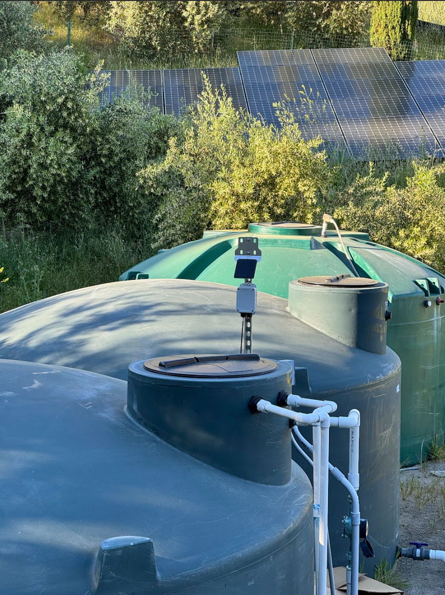 Automated monitoring node connected to water level sensors and monitoring a large green tank