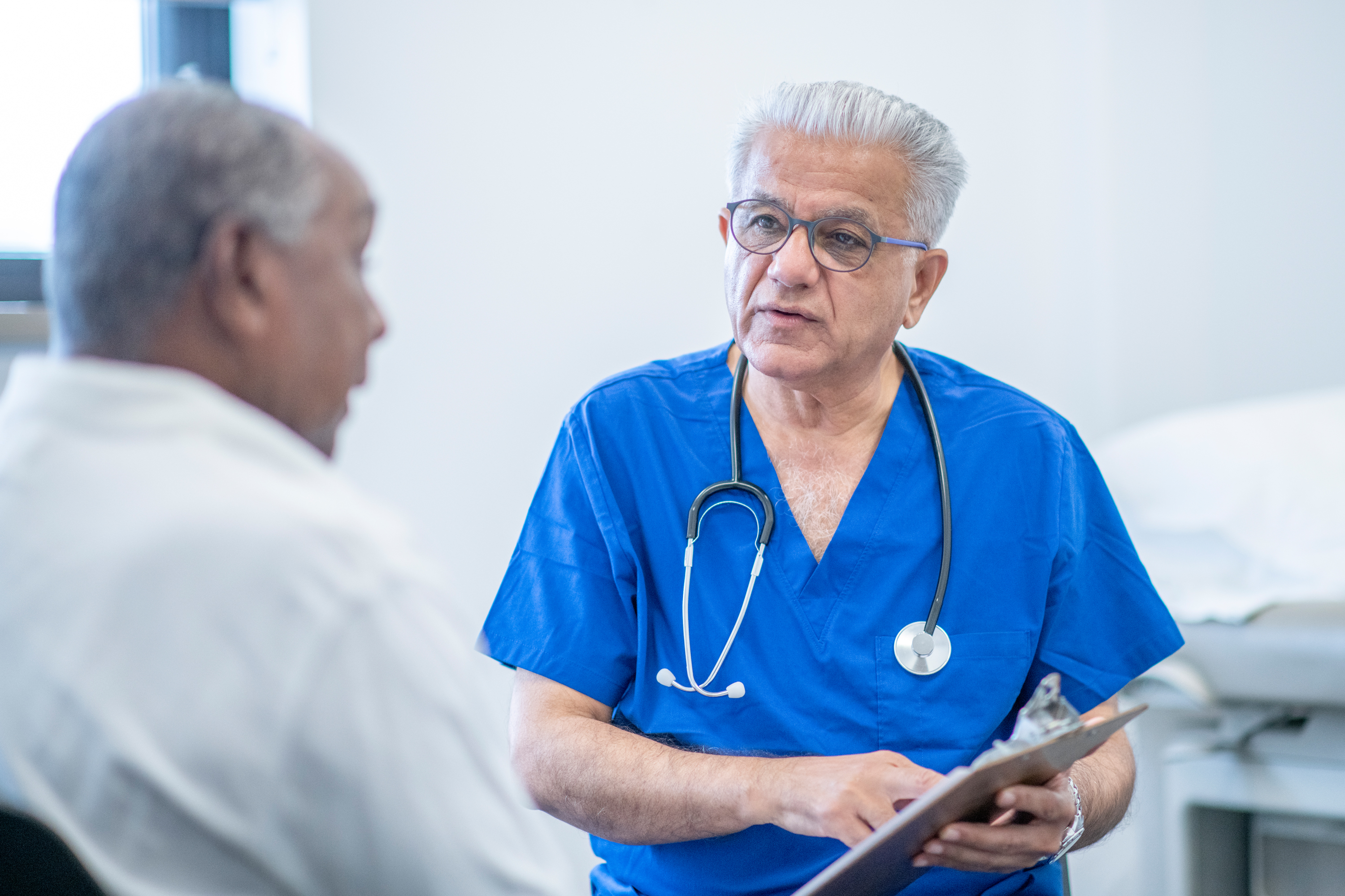 Doctor discussing PSA results with an older male patient in a clinical setting