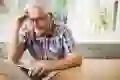 Confused senior man using laptop