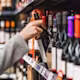 A person taking a bottle of alcohol off the shelf.