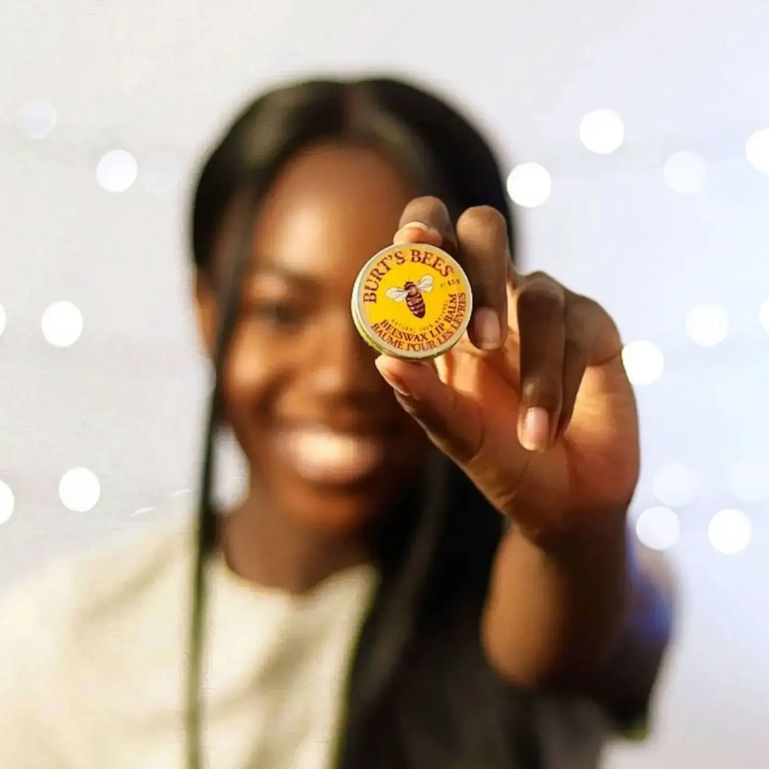 woman holding out a tin of lip balm