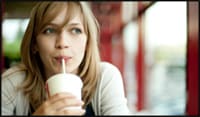 Photo of young lady sipping beverage through a straw.