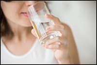 Photo of lady drinking water from a glass.