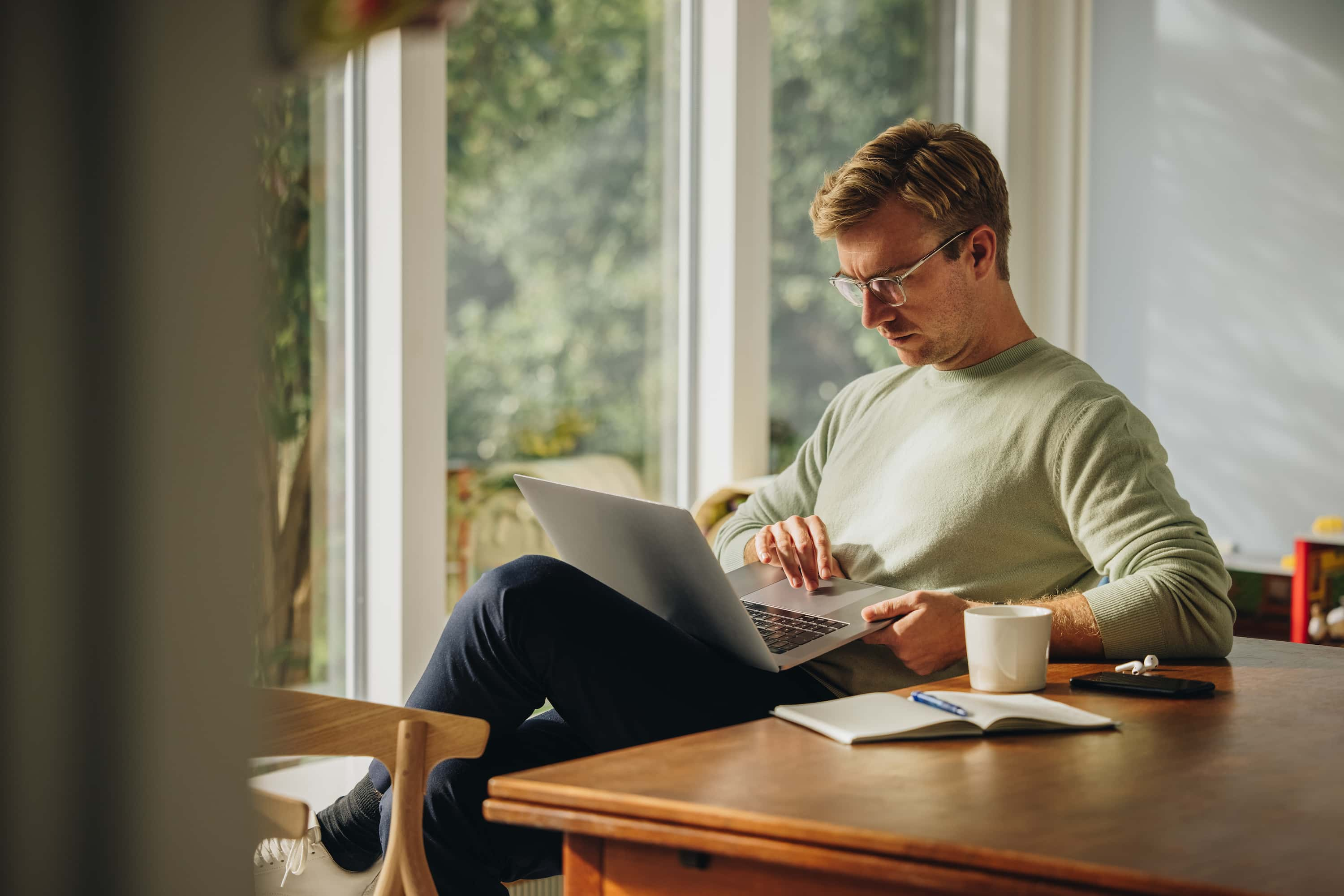 Man sitting at a table with a laptop in his lap