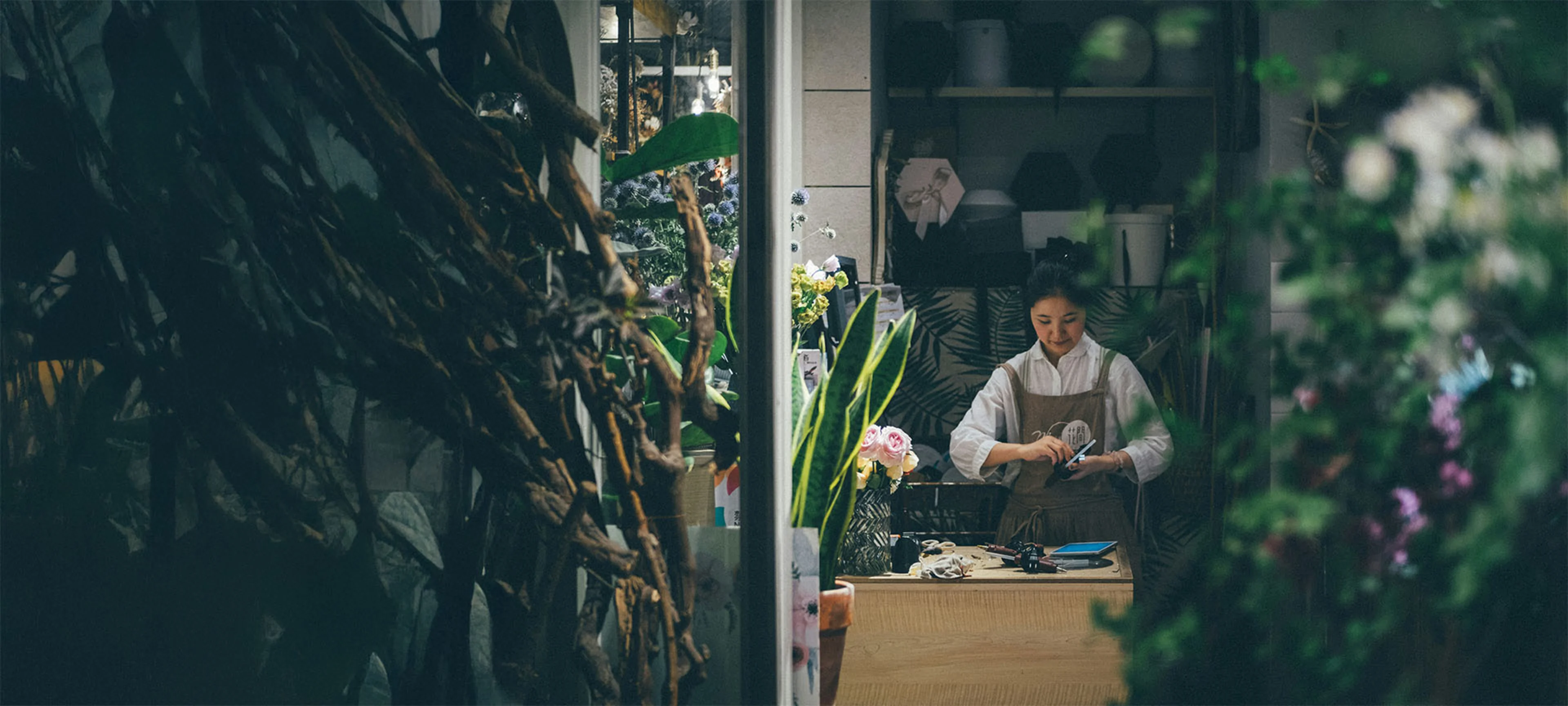 Smiling woman tending plants in her small business shop, representing success with a Small Business Line of Credit