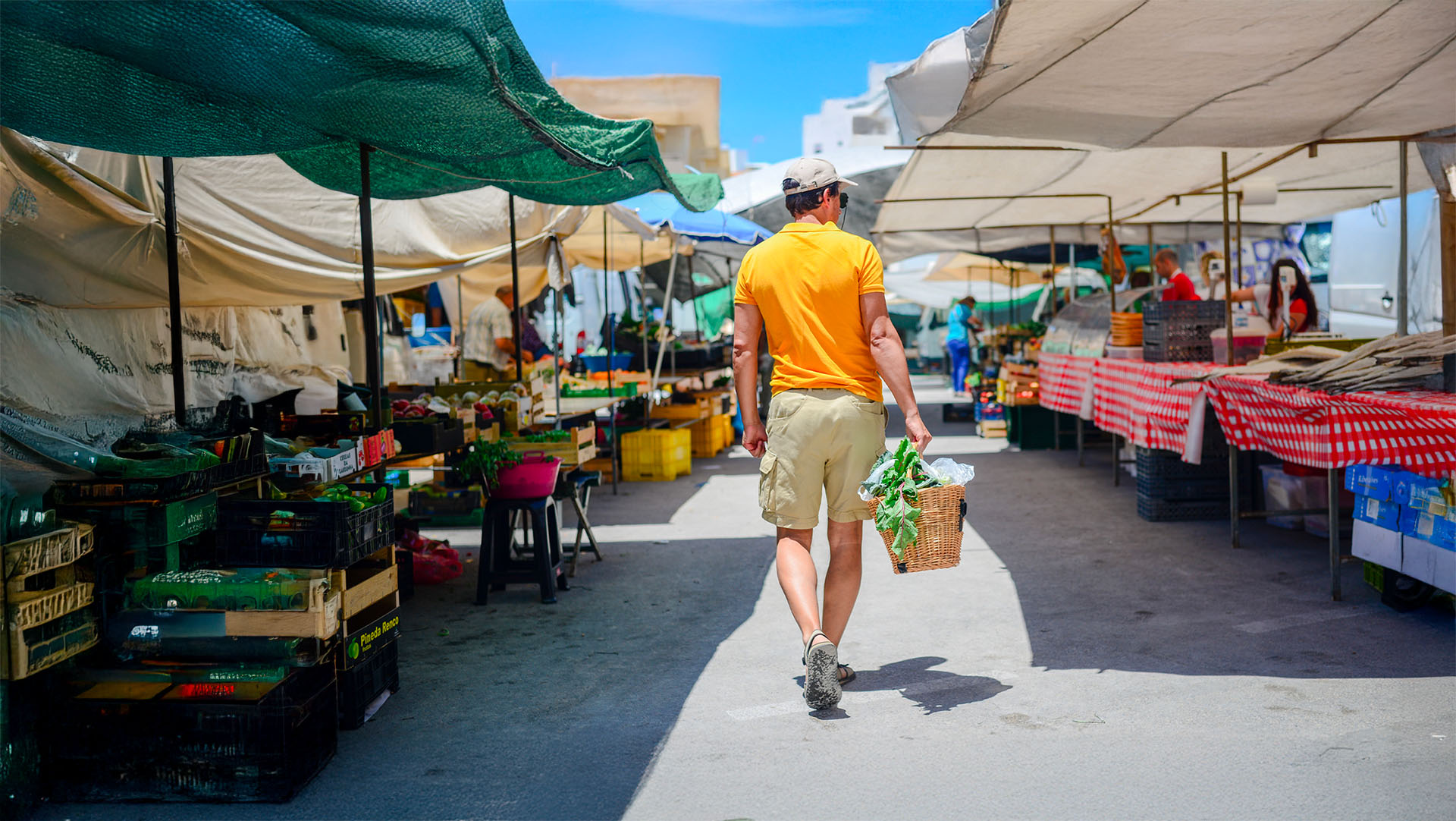 Man walking through a Colorado farmers market, illustrating the convenience of opening a checking account online with a debit card that has no monthly fees and offers rewards.