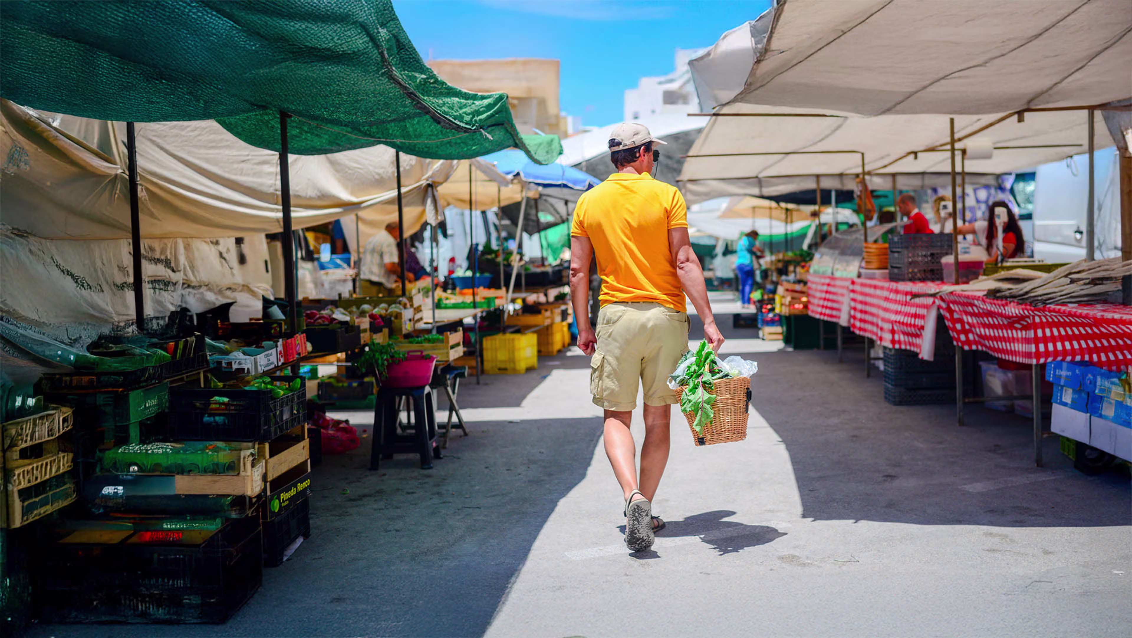 Man walking through a Colorado farmers market, illustrating the convenience of opening a checking account online with a debit card that has no monthly fees and offers rewards.