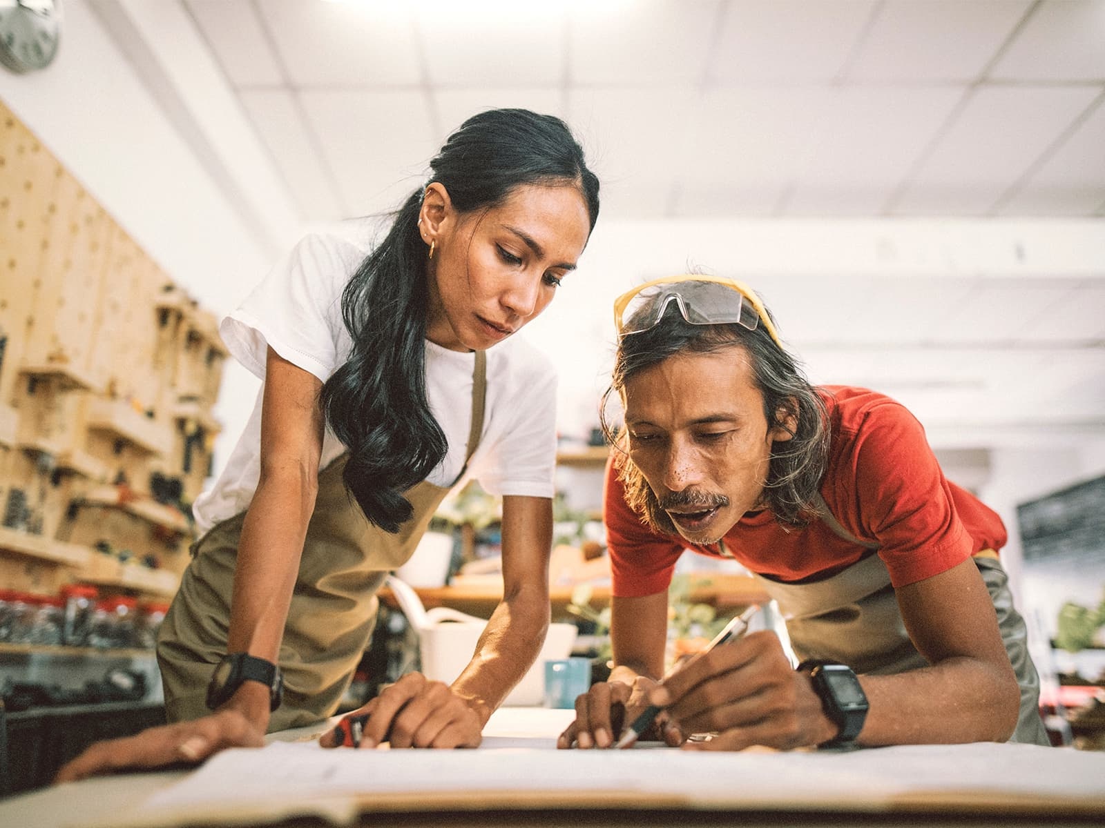 Man and woman drawing out plans in a wood shop