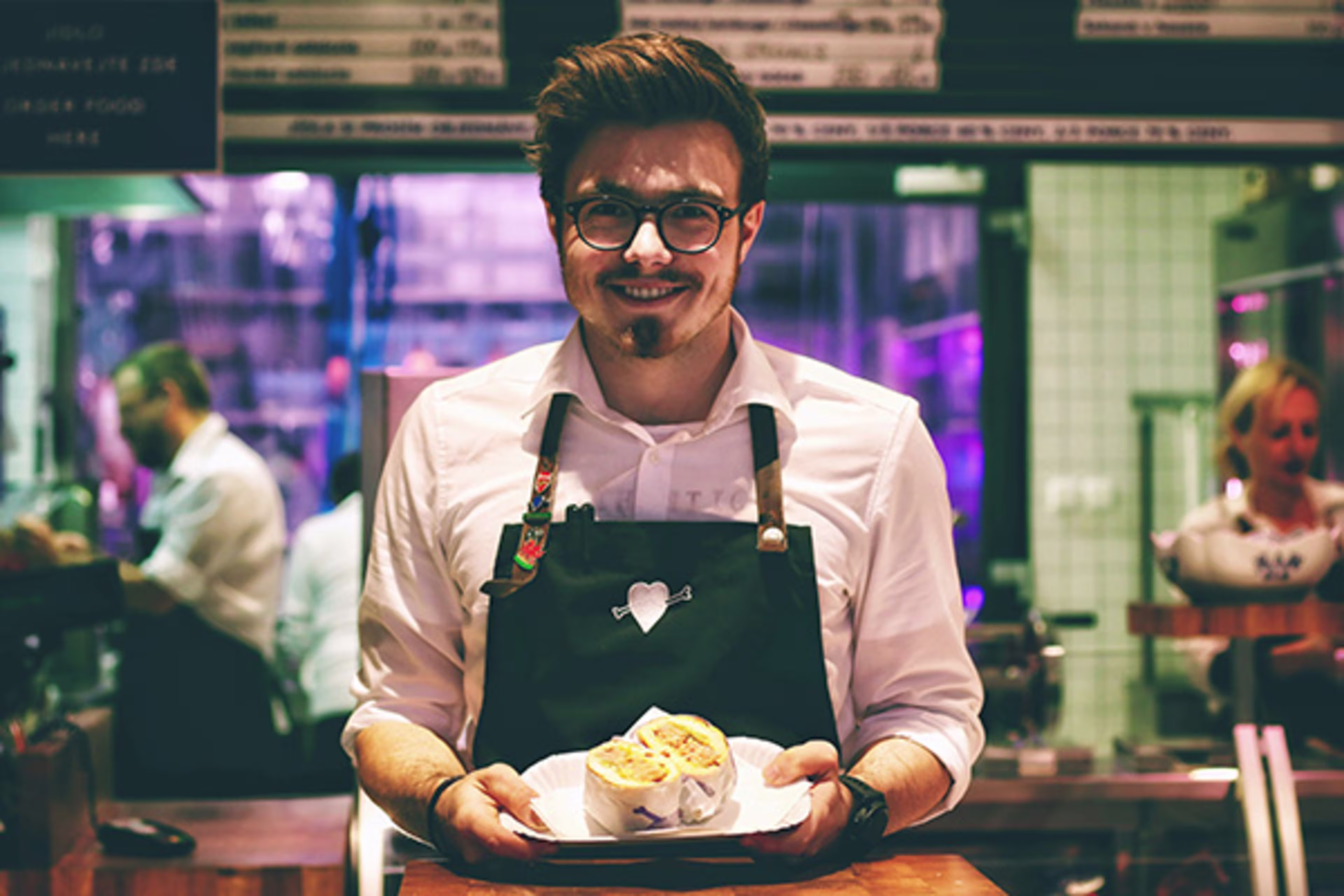 Small business owner holding freshly prepared food, representing a local restaurant’s success and growth.