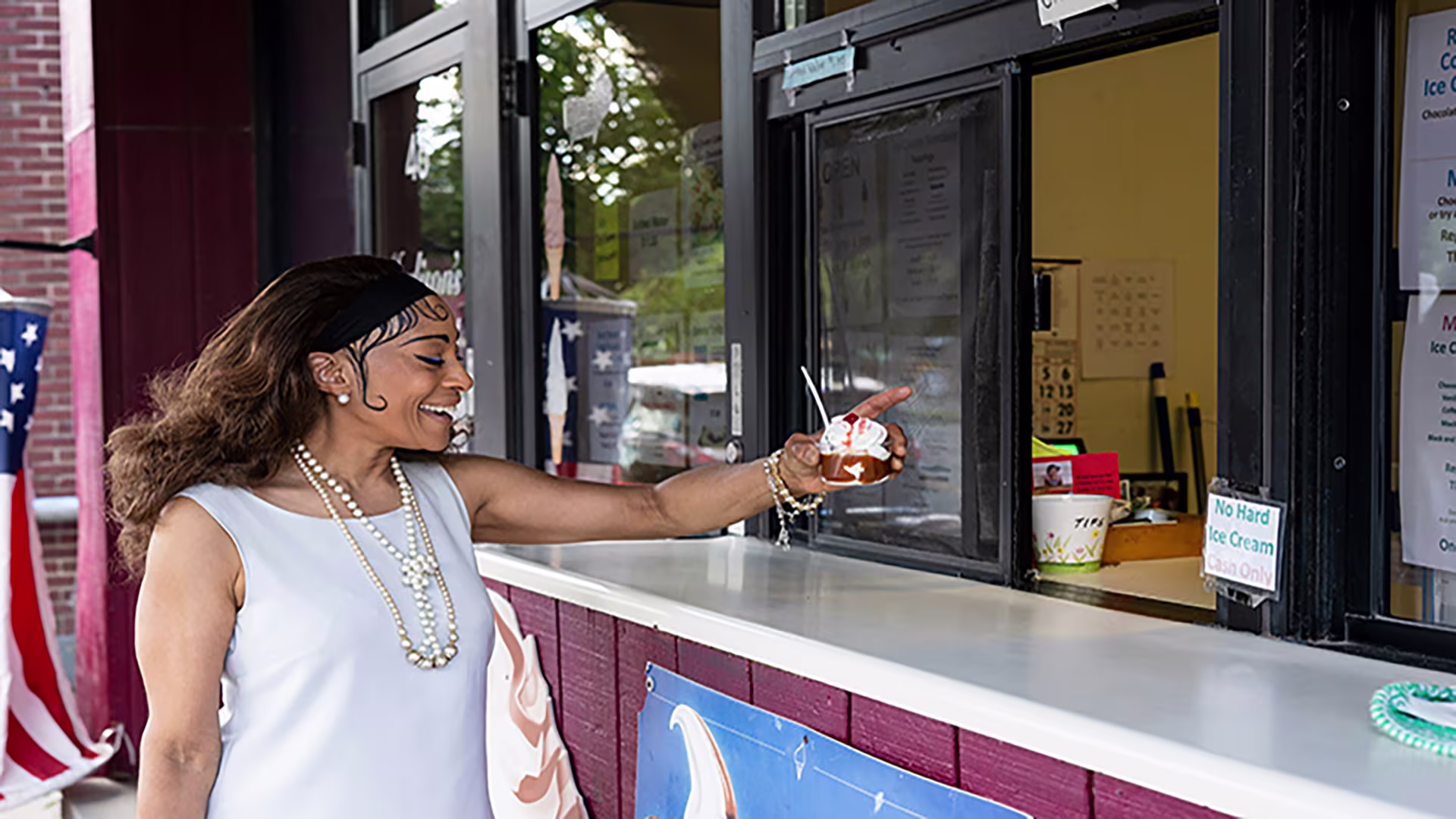 A woman smiling as she receives ice cream from a vendor, holding out her Westerra Business Rewards credit card to pay — representing small business support.