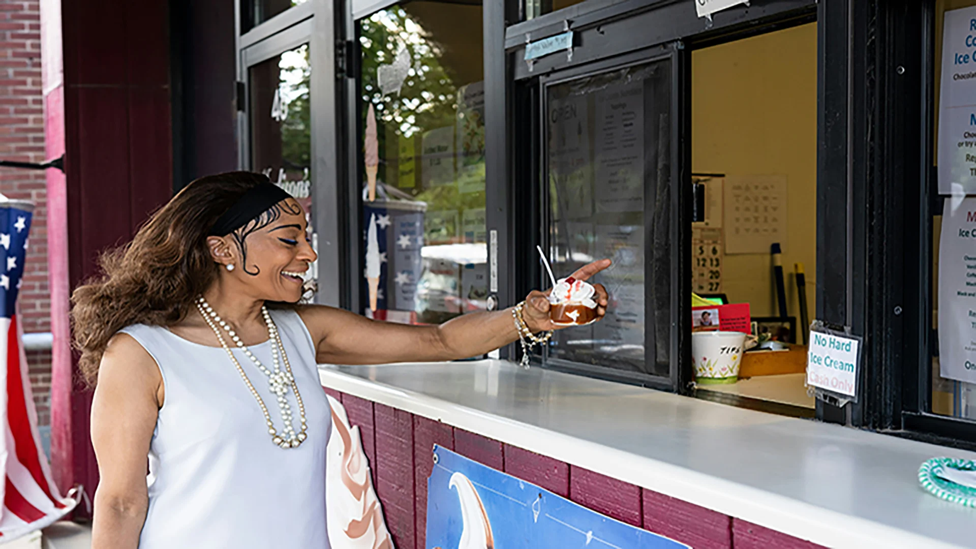 A woman smiling as she receives ice cream from a vendor, holding out her Westerra Business Rewards credit card to pay — representing small business support.