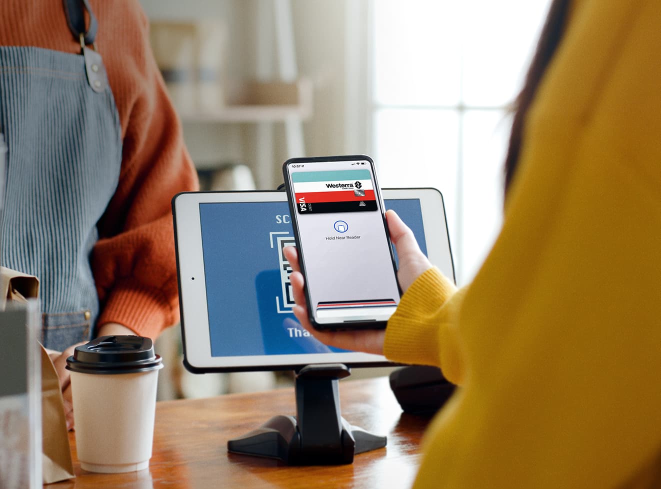 Close up of a woman holding her phone up to a store payment kiosk