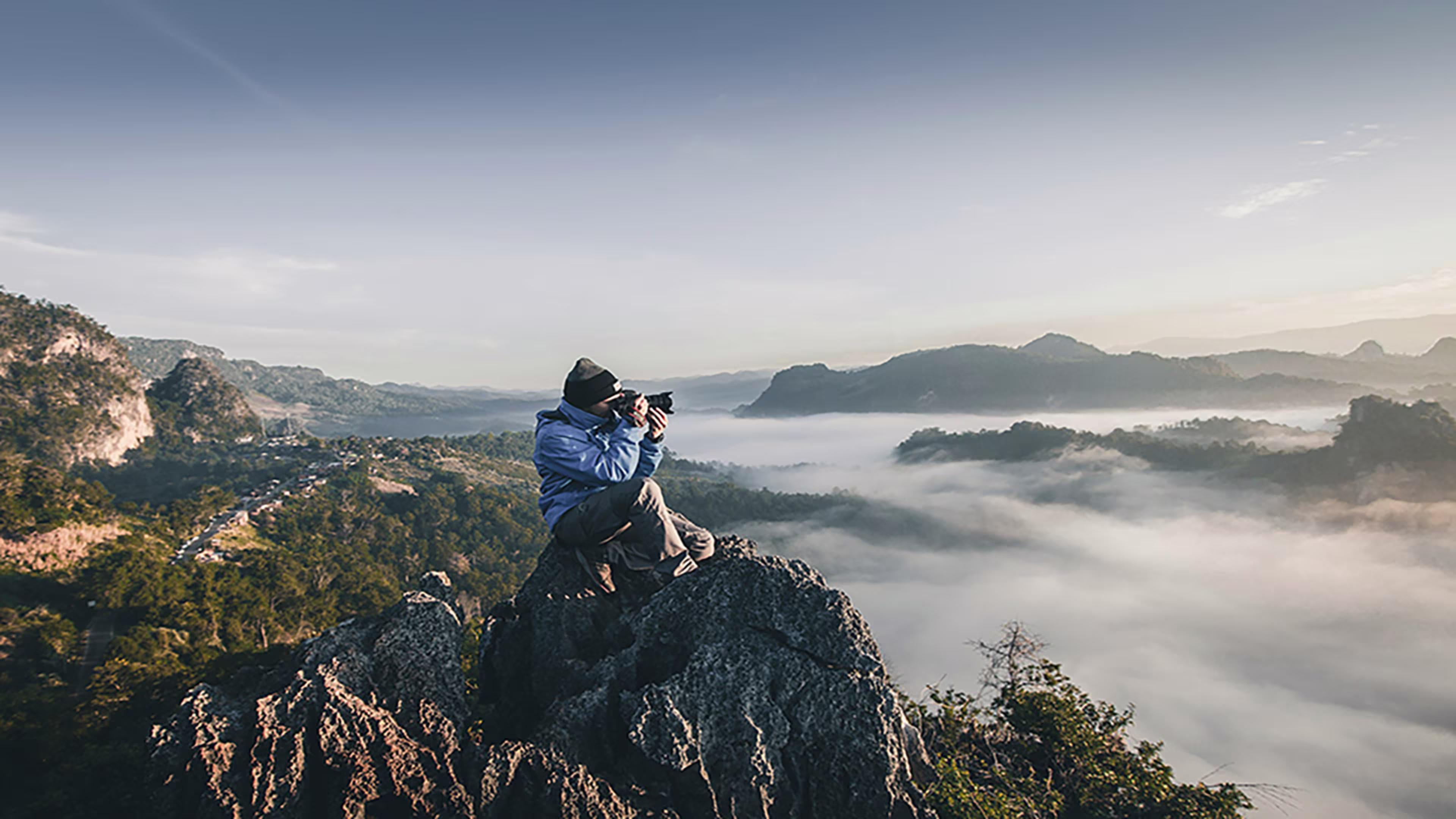Confident small business owner capturing success on a mountain peak, symbolizing growth and financial empowerment.