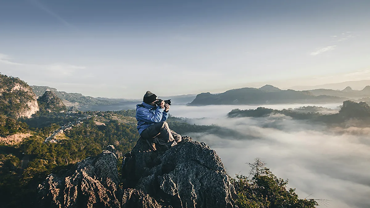 Confident small business owner capturing success on a mountain peak, symbolizing growth and financial empowerment.