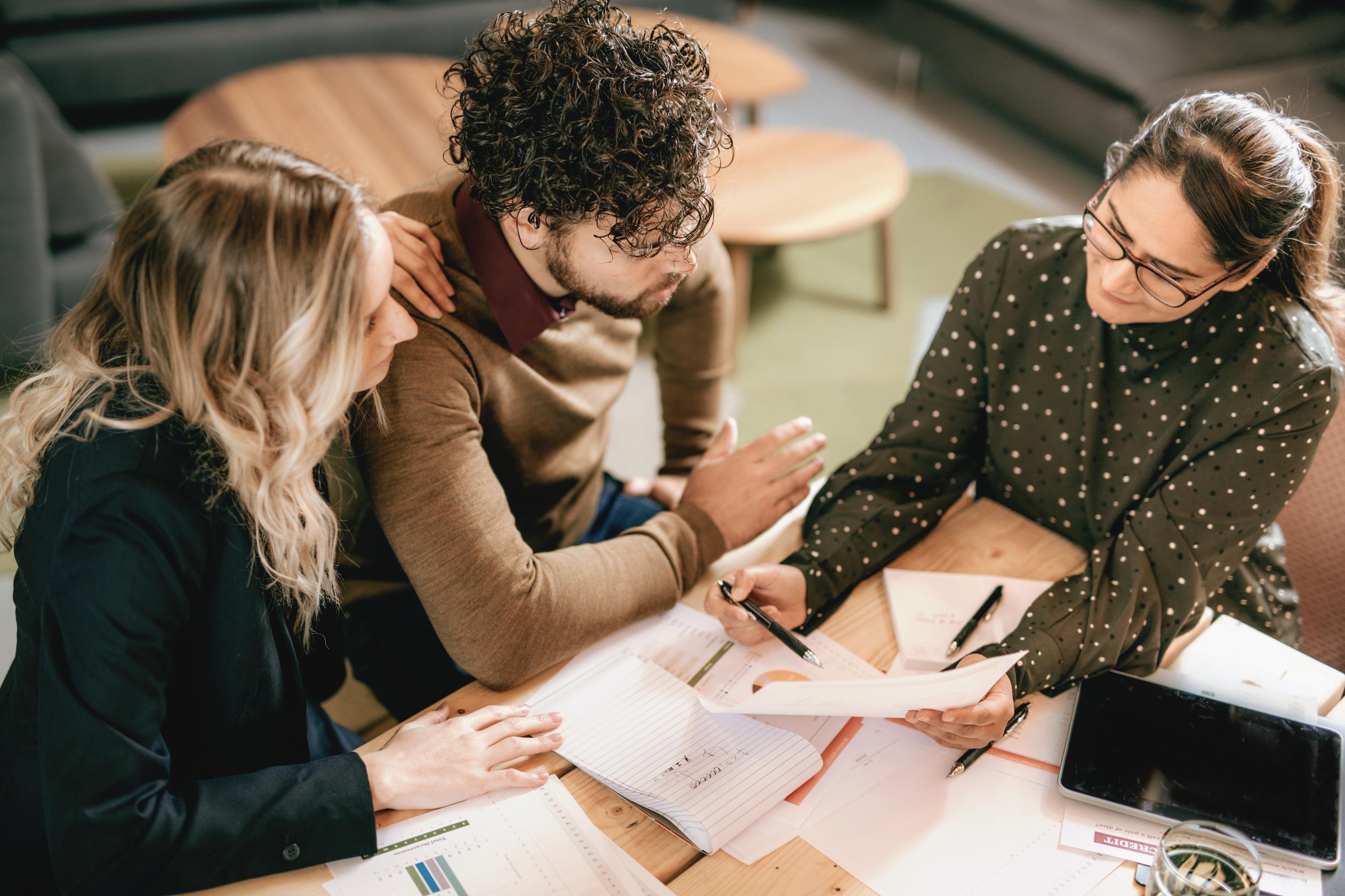 Three people at a table looking at paperwork