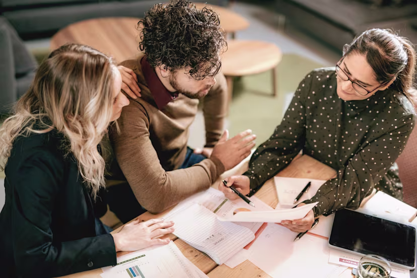 Three people at a table looking at paperwork