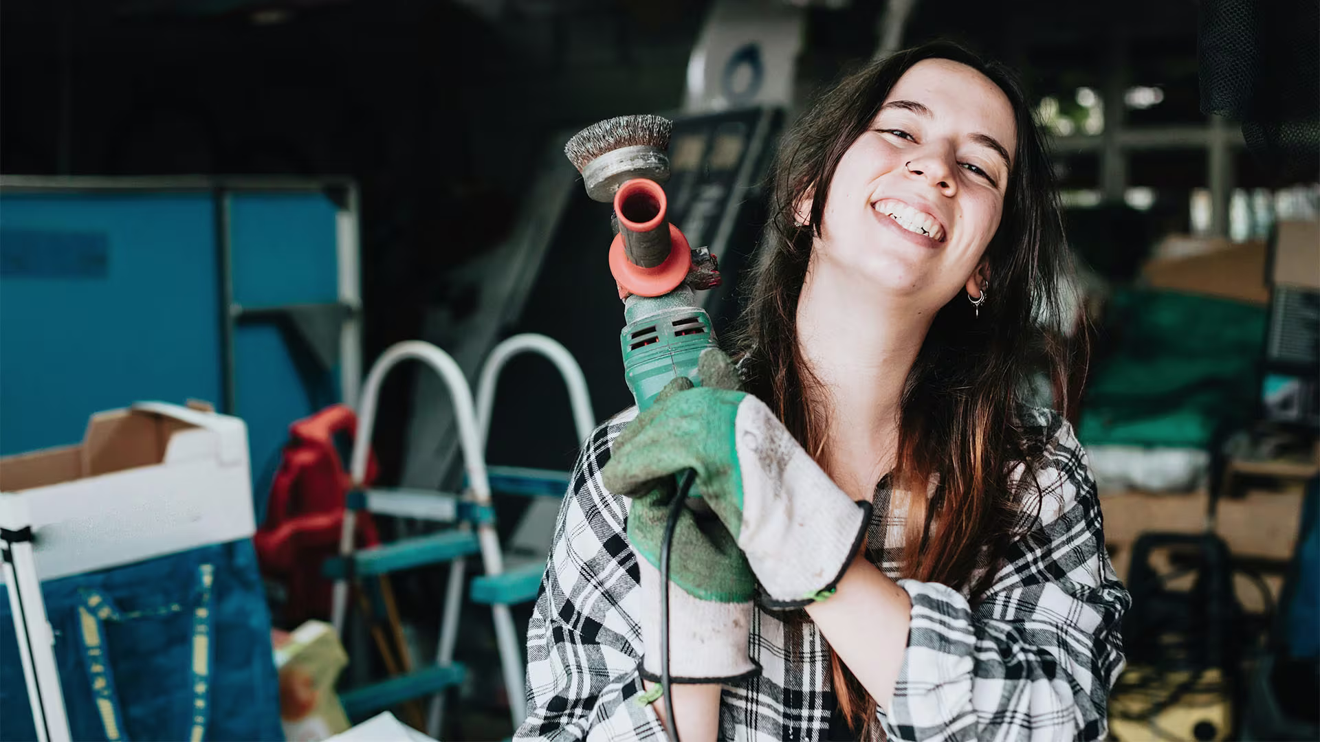 Smiling woman holding a power tool, representing a confident small business owner in a skilled trade or construction business