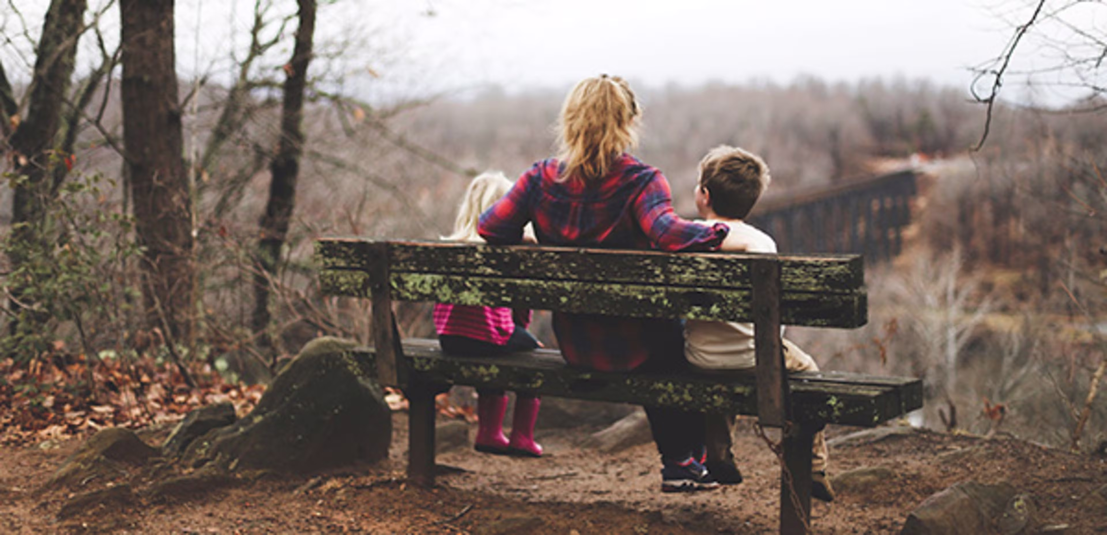 Family sitting on a bench looking out at a beautiful view.