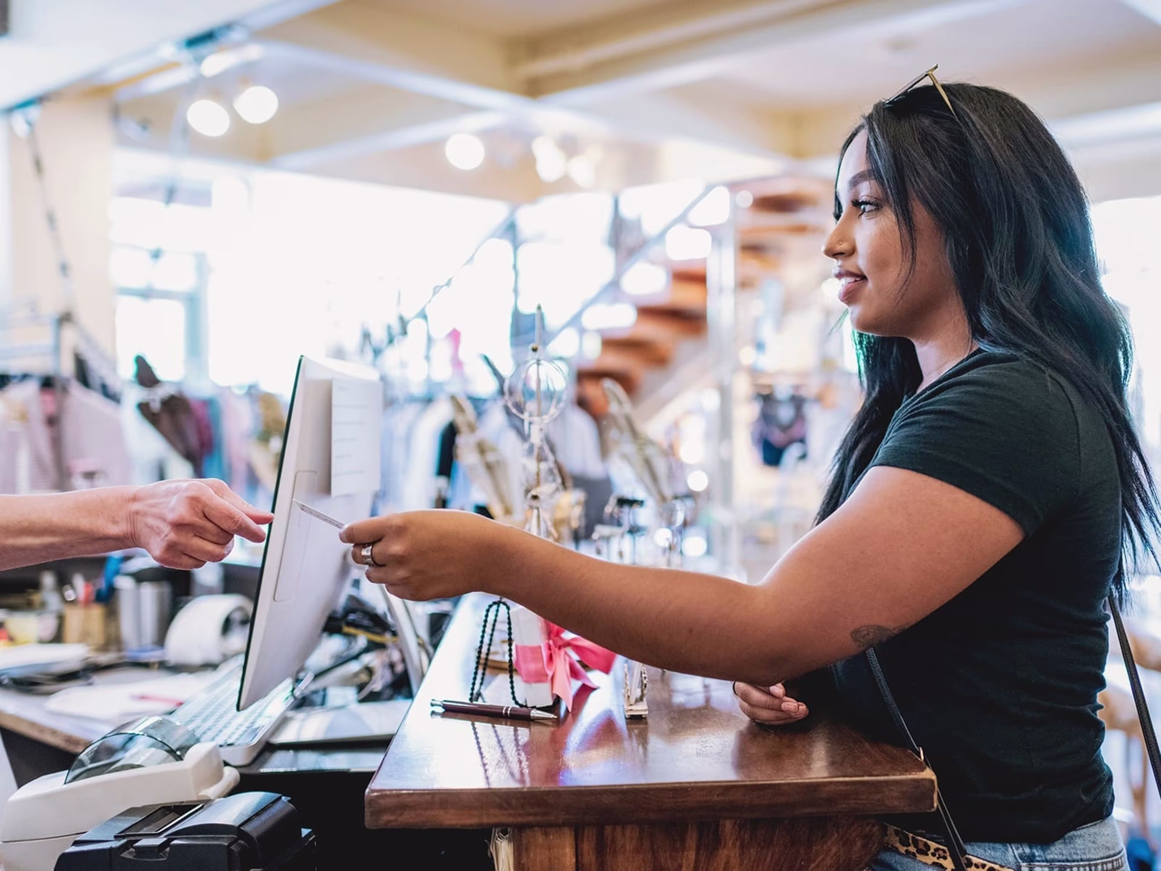 Woman at counter handing her card to a cashier