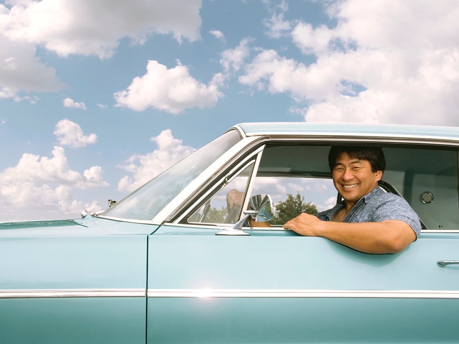 Man smiling in blue vintage car