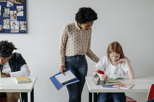 Photo of a teacher helping a kid at their desk