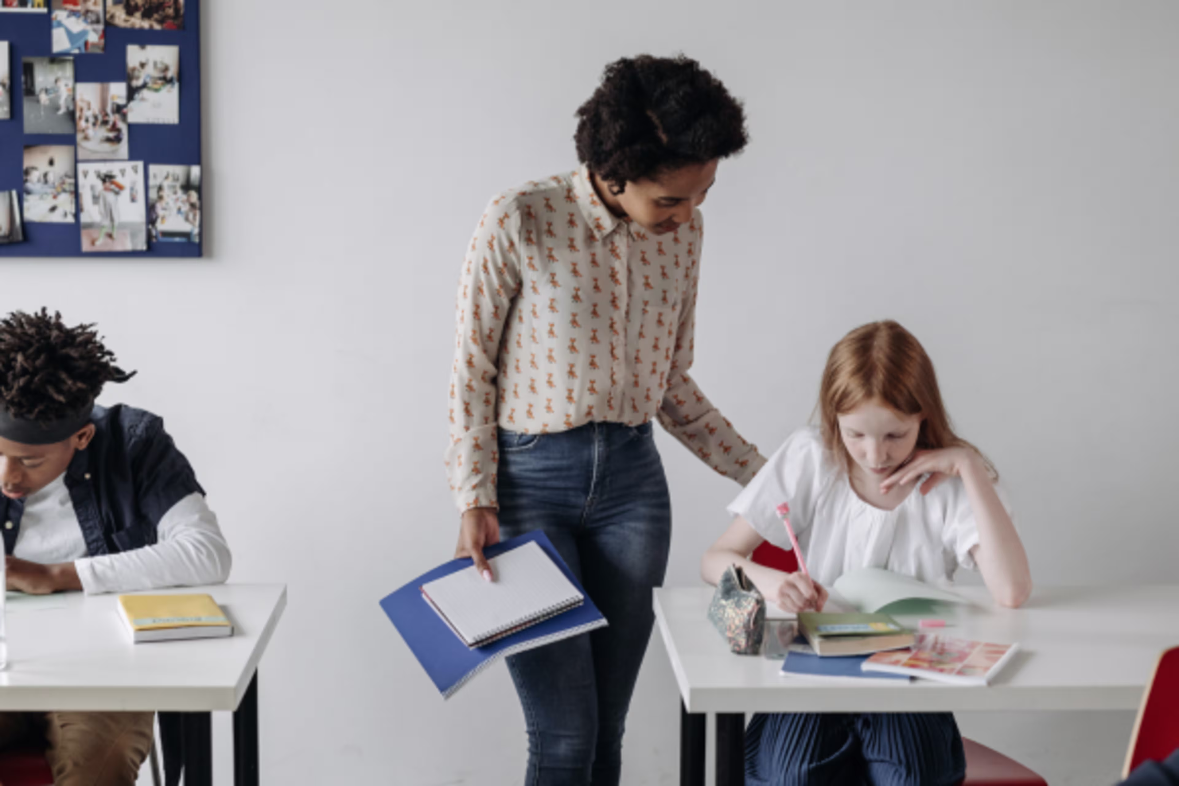 Photo of a teacher helping a kid at their desk