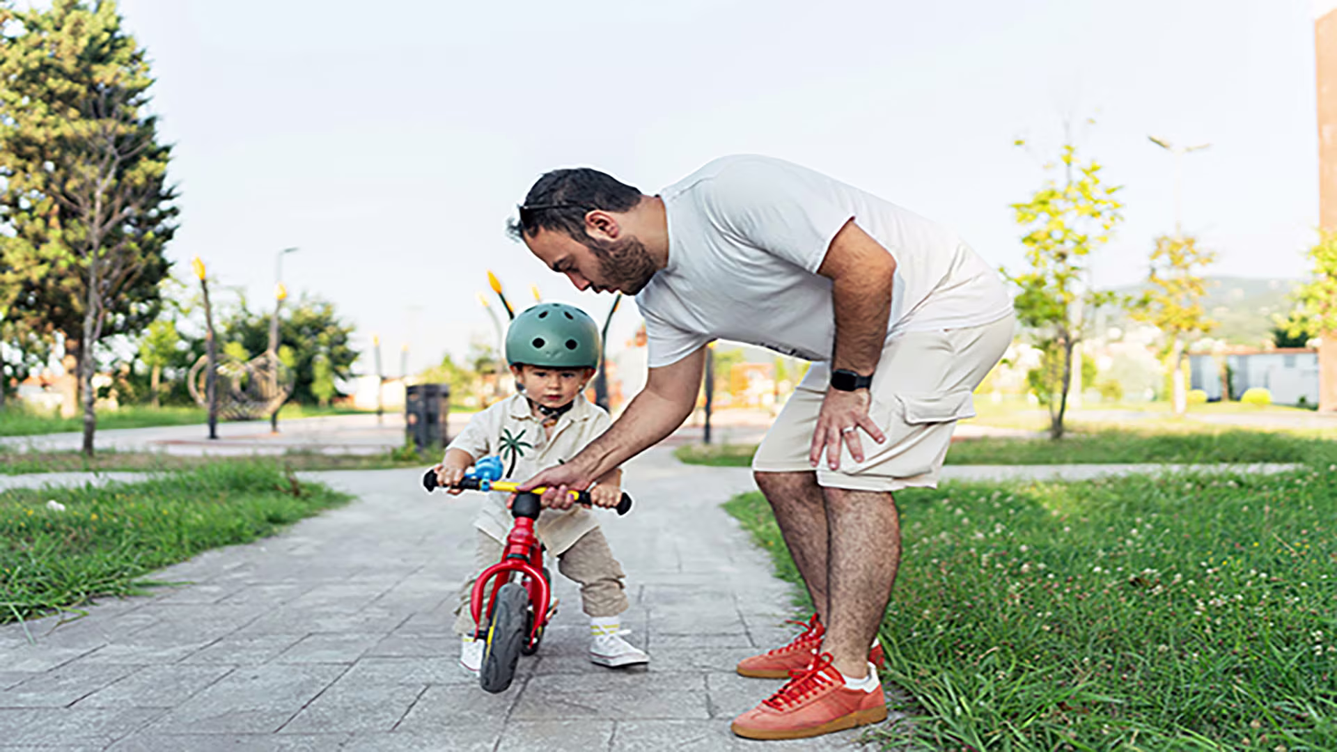 Man helping his child ride a bike, symbolizing support and new beginnings