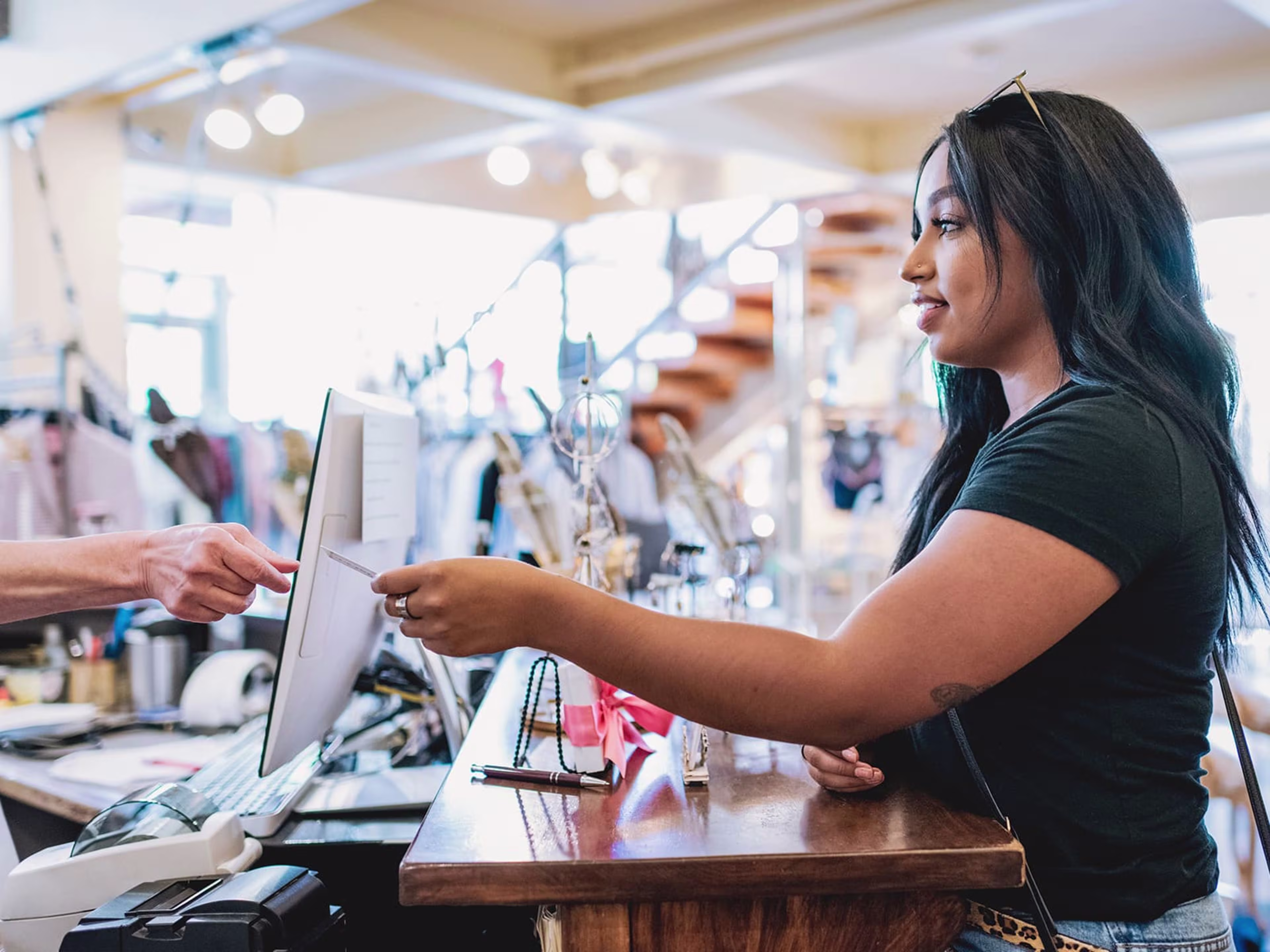 Woman at counter handing her card to a cashier