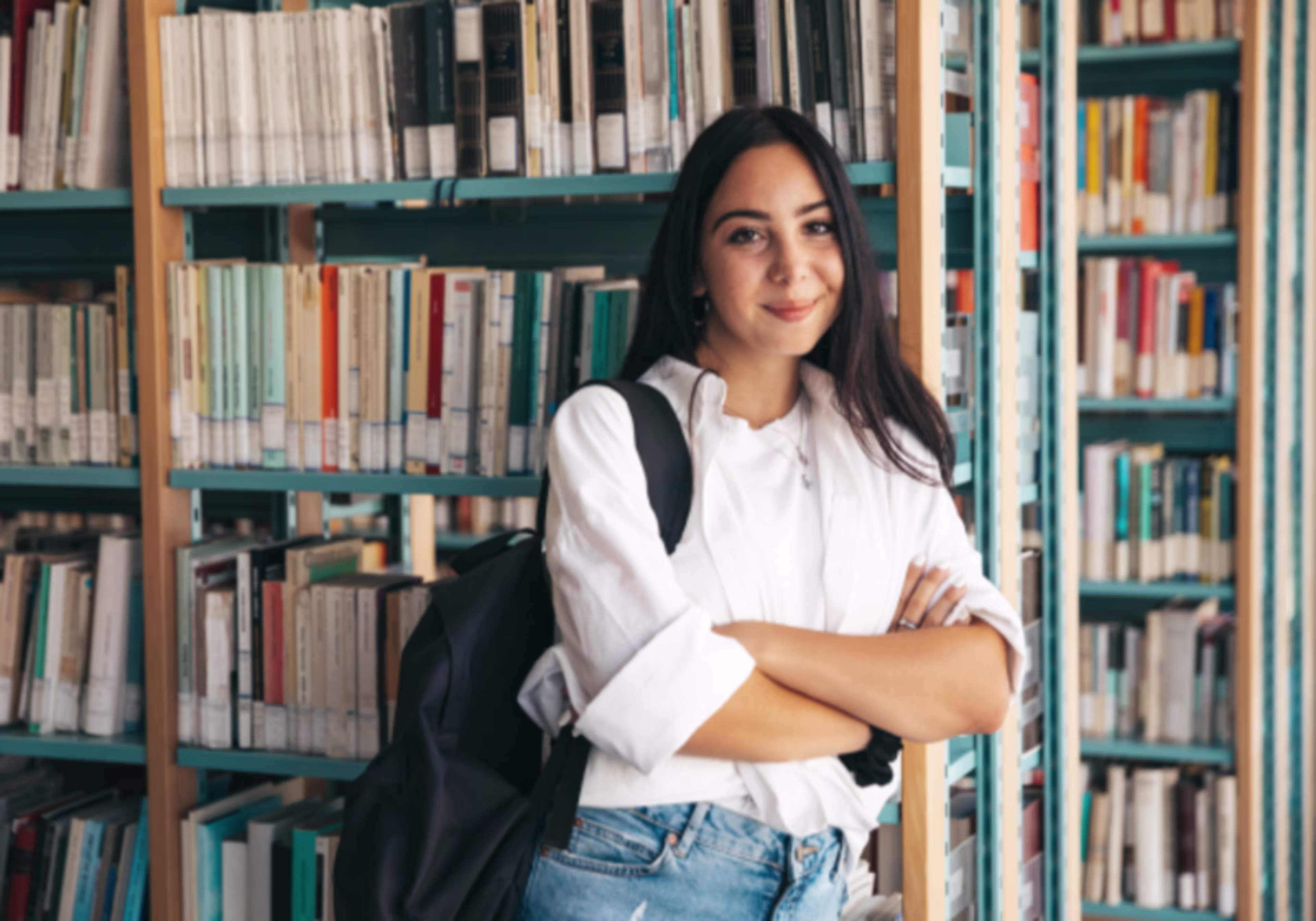 Photo of a young adult woman with a backpack in a library