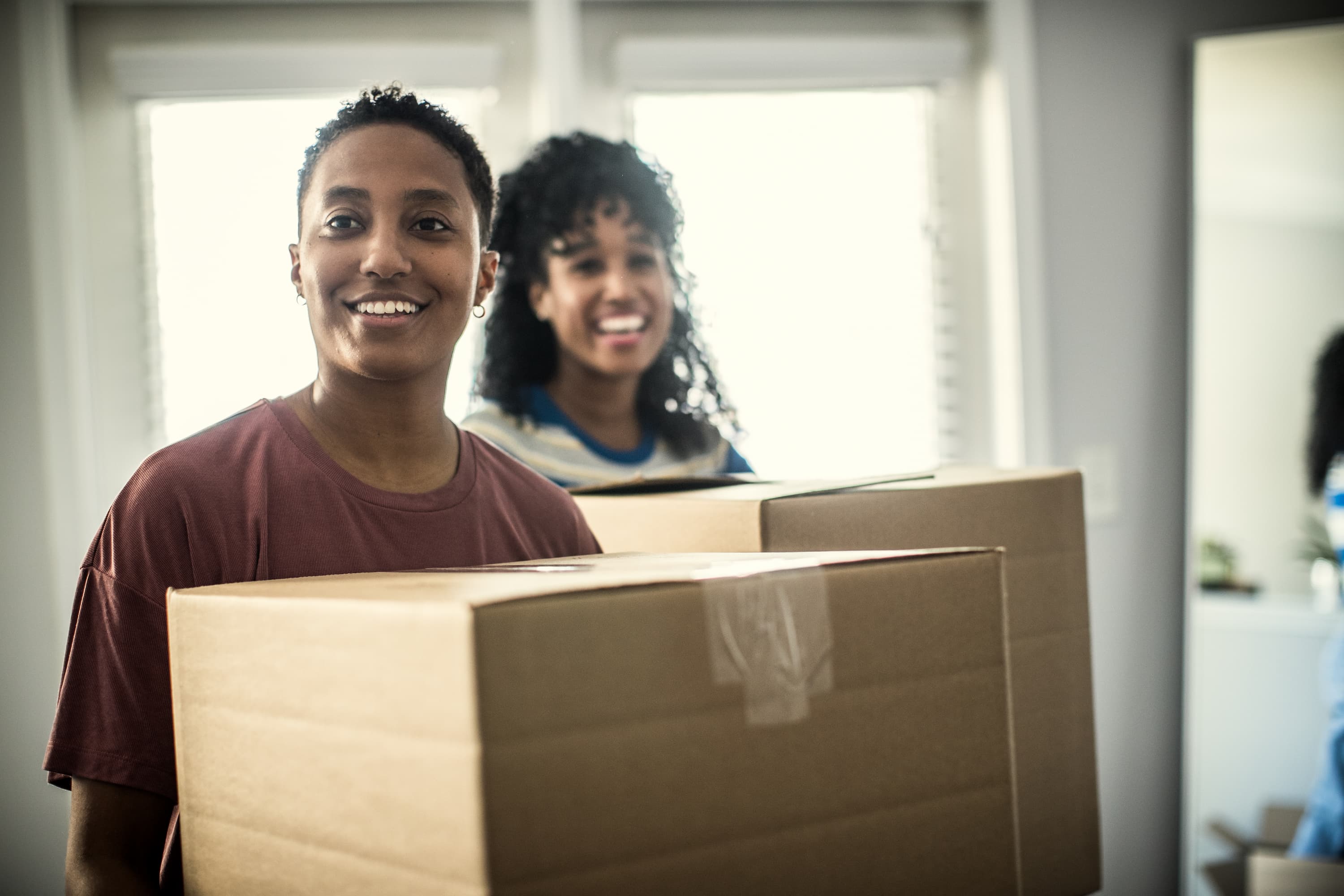 Two women holding boxes to move in