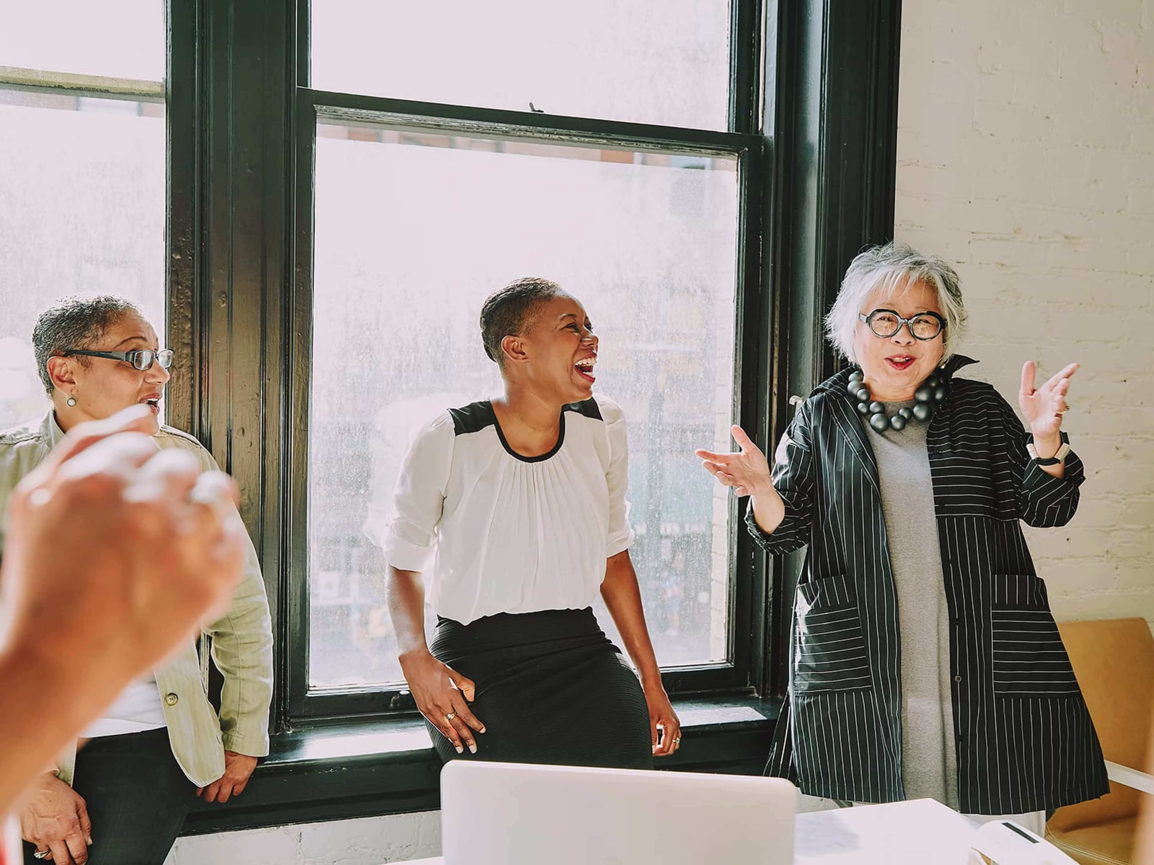 Three women laughing in a conference room