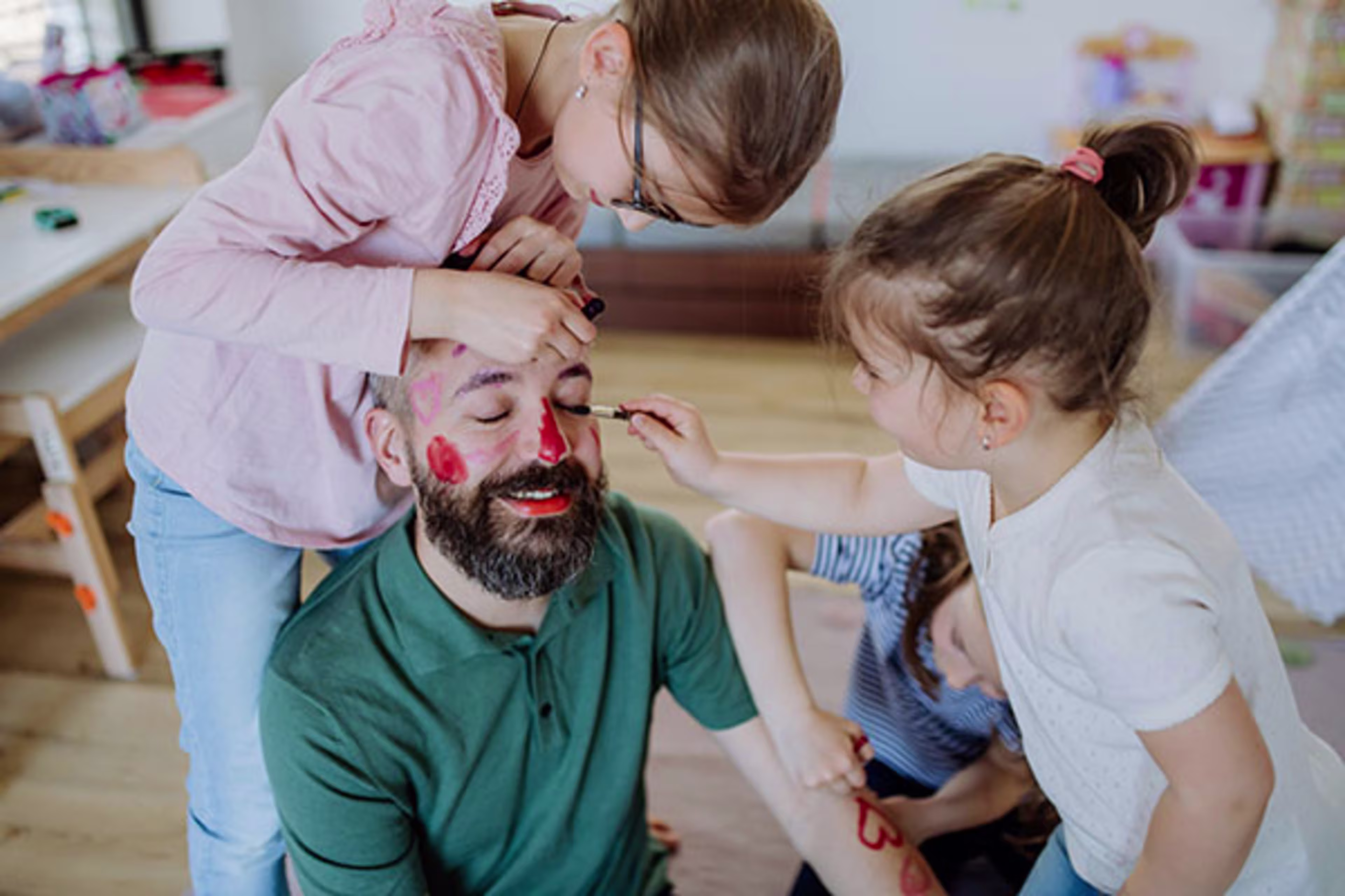 Man enjoying playful moments with his kids as they paint his face, symbolizing the joy of homeownership and family life—supported by options like Adjustable-Rate Mortgages (ARM), 5-Year ARM, and refinancing opportunities.