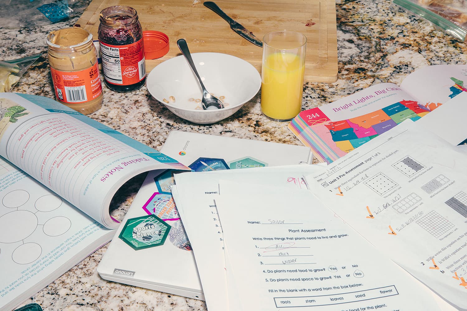 Countertop with open peanut butter and jelly jars, bowl of cereal, glass of orange juice, and multiple open textbooks