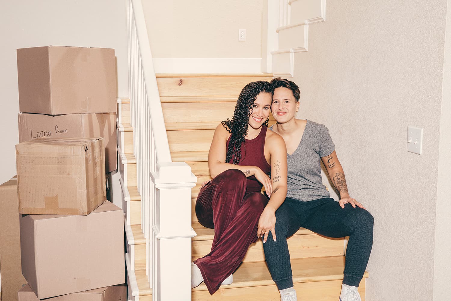 Cute lesbian couple sitting on the stairs of their new home