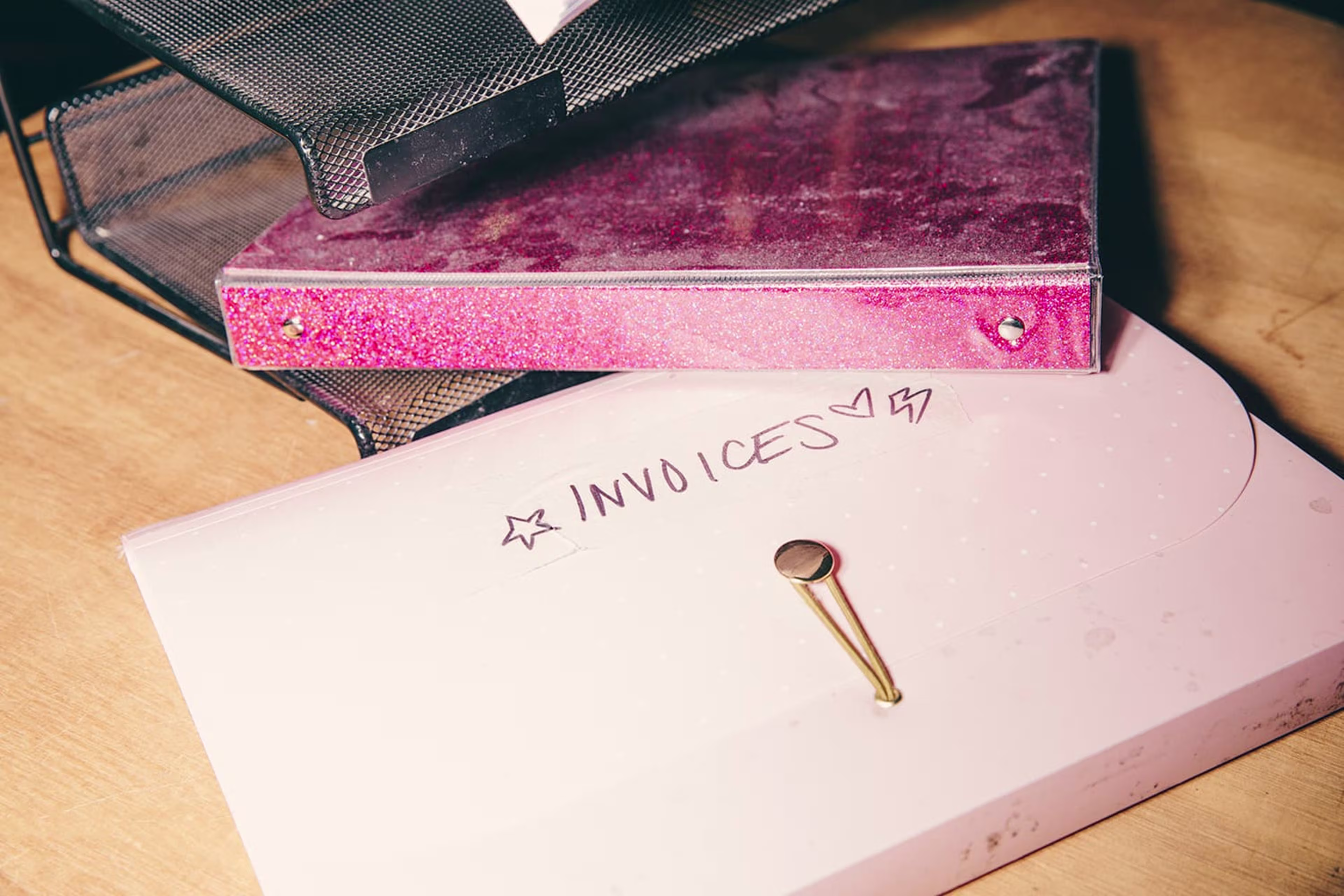 Two pink three-ring binders; one labelled "Invoices"