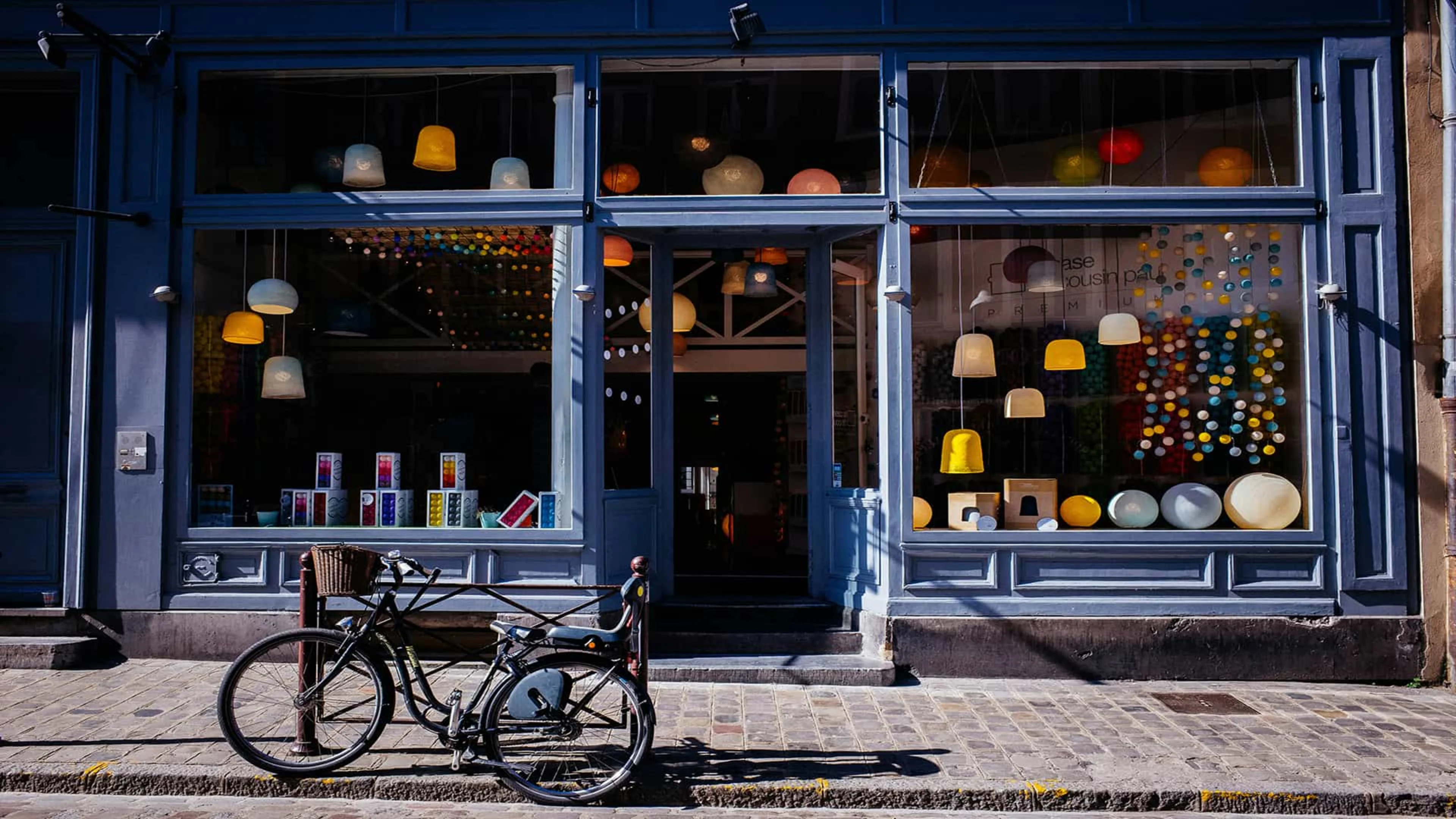 A charming local storefront with large windows and a bicycle parked on the sidewalk out front, symbolizing small business and community life.
